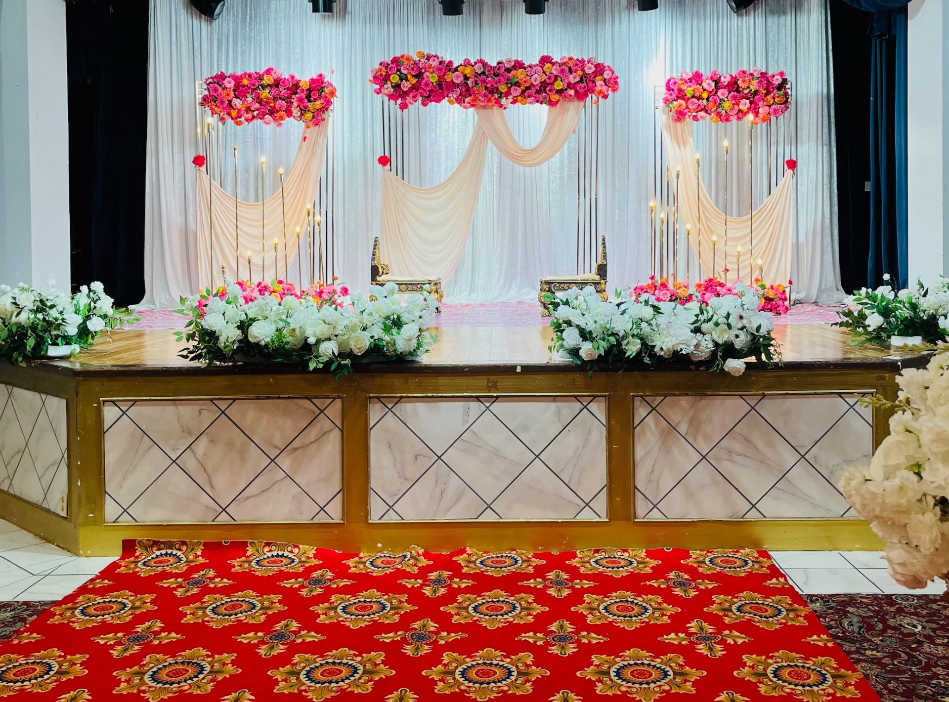 Pink floral reception with cream draping and gold seating