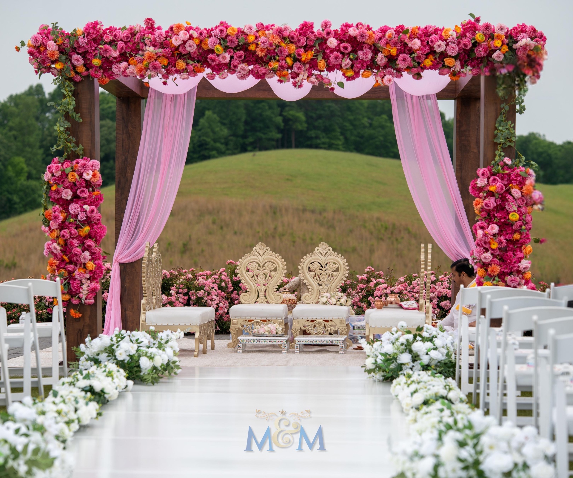 Outdoor pink floral wedding arch and monogrammed aisle