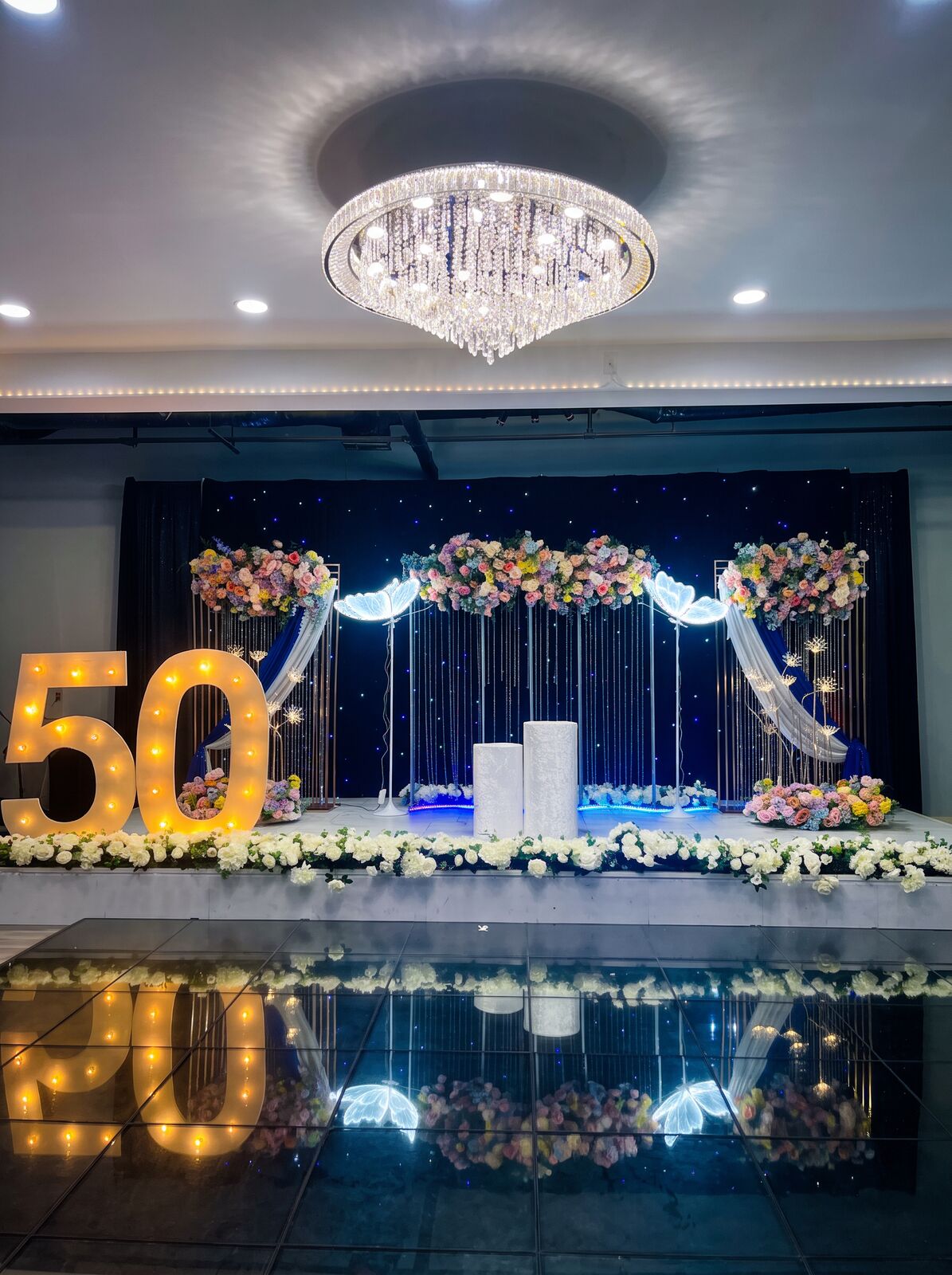 Fiftieth birthday stage with florals and glowing butterflies