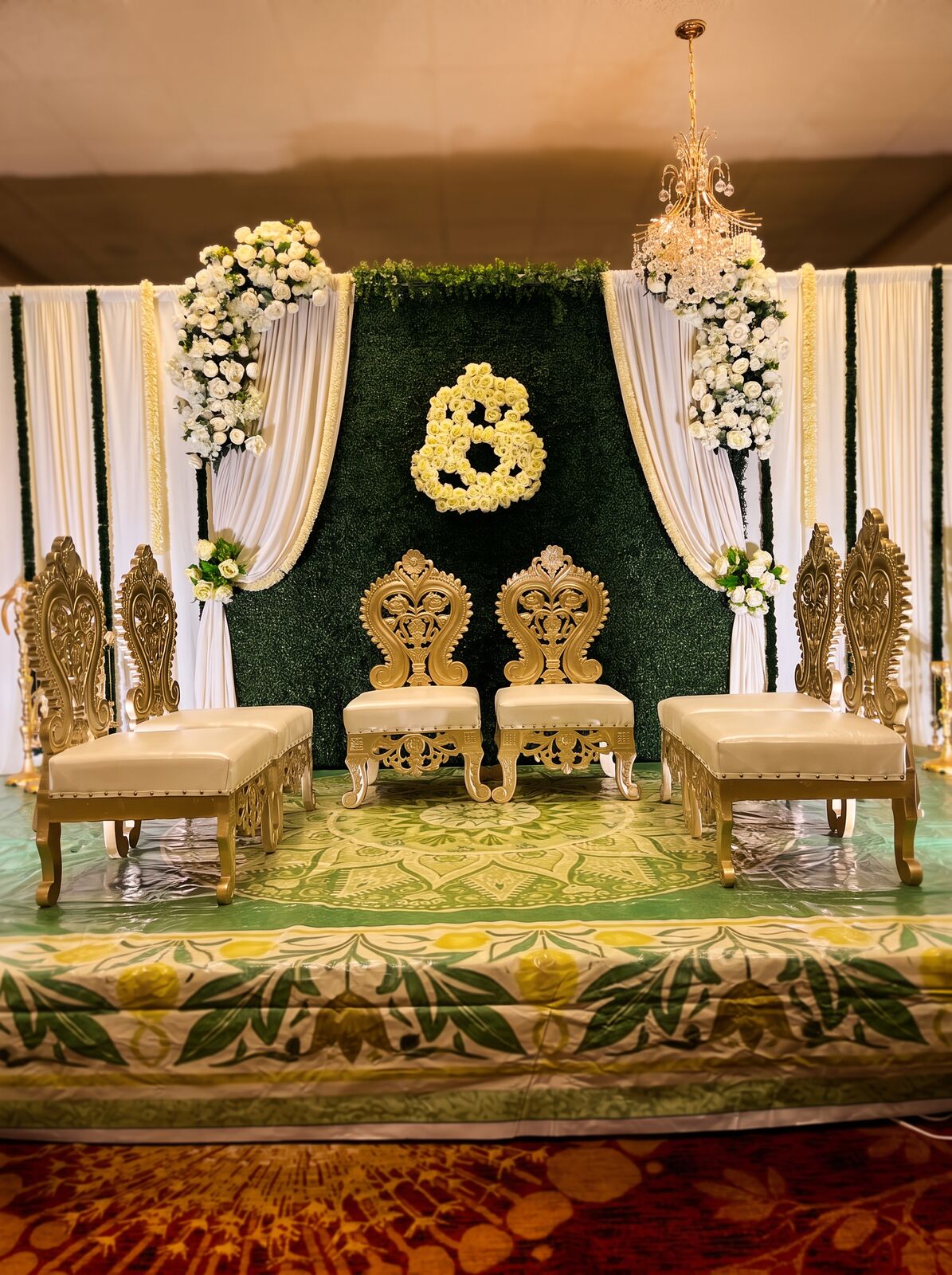 Greenery wall with floral monogram and gold seating
